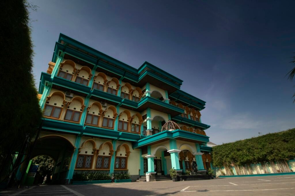 Gedung bertingkat bercat hijau dengan banyak jendela dan balkon
