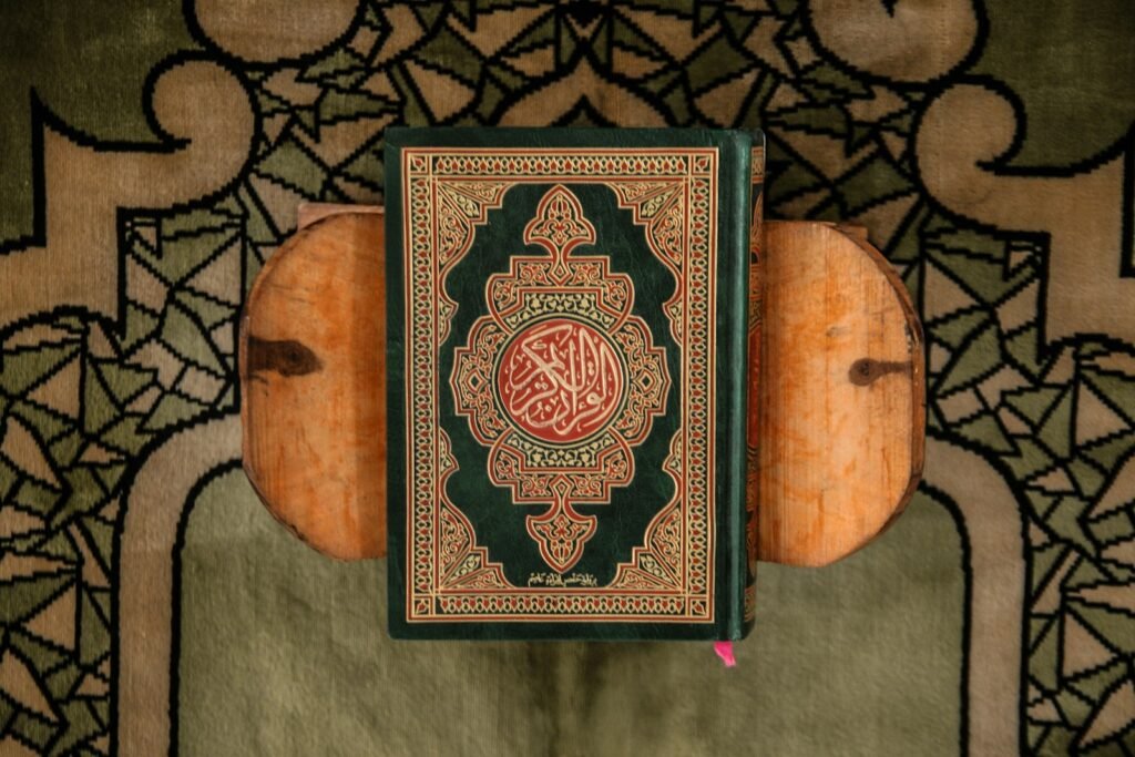 Mushaf hijau di atas rehal kayu di atas sajadah bermotif