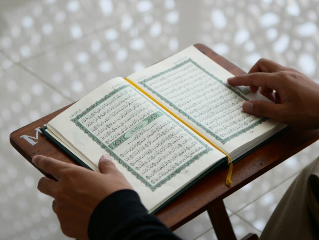 Tangan di atas mushaf yang terbuka di rehal