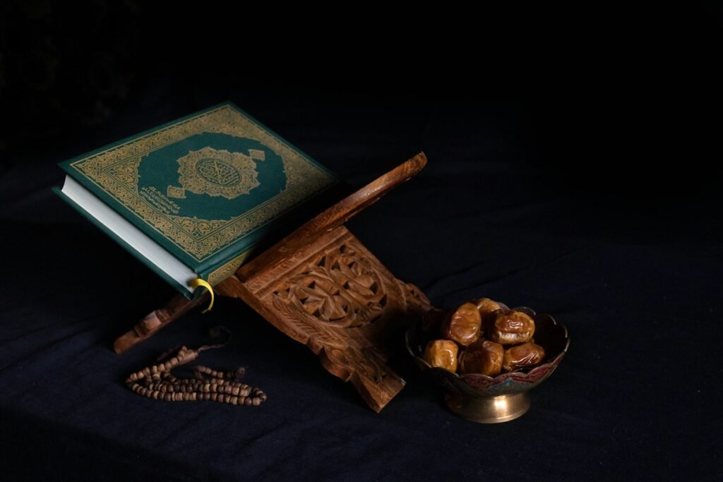 Mushaf hijau di atas rehal kayu, kurma, dan tasbih