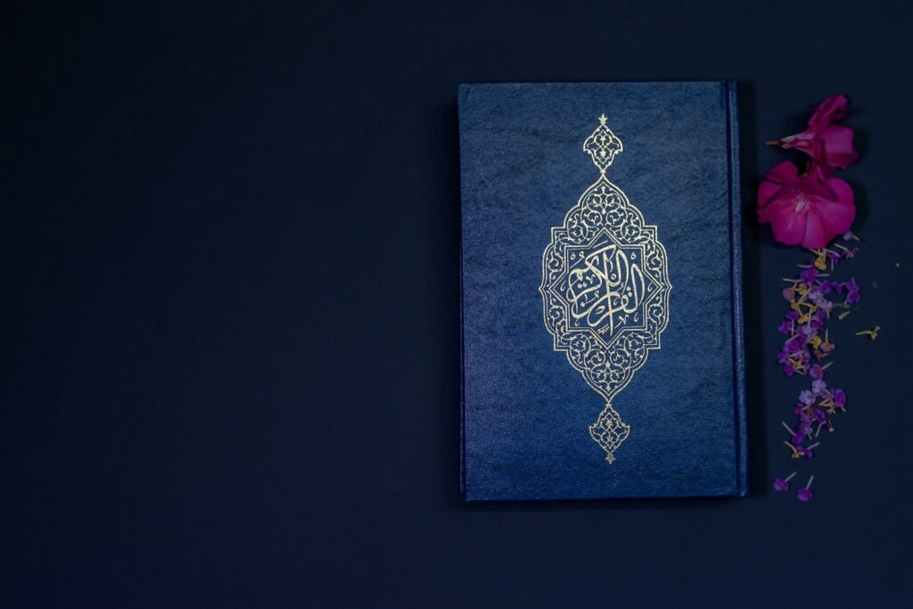 Mushaf bersampul biru di samping bunga ungu