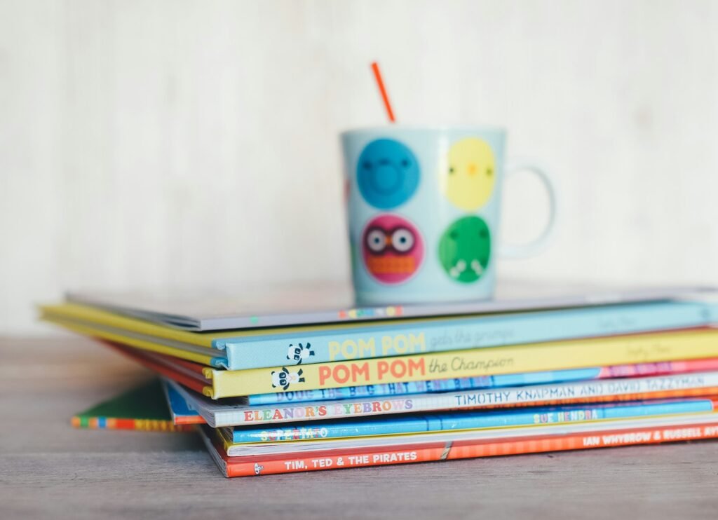 Tumpukan buku cerita anak warna-warni dengan cangkir bergambar di atasnya